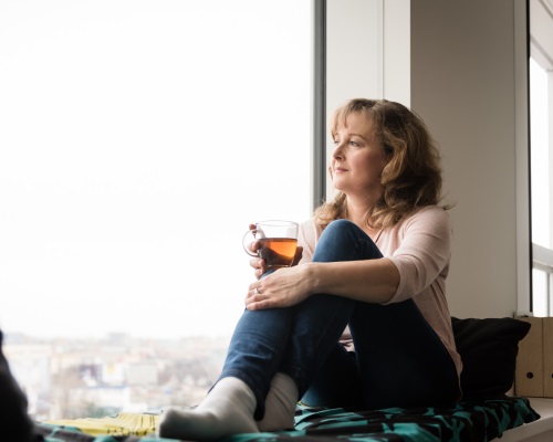 Senior woman drinking tea and looking through window