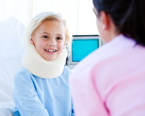 Little girl with a neck brace talking with a nurse