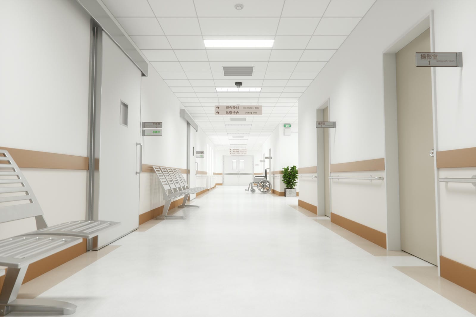 Clean and bright hospital hallway with benches, signs in Japanese, and a wheelchair near the end of the corridor.